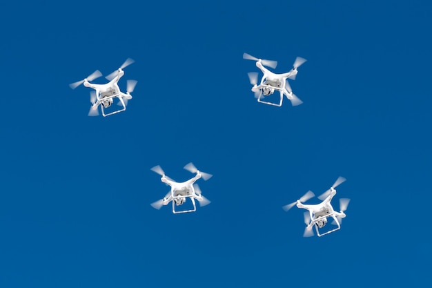 Na niebieskim niebie roi się od dziesiątek dronów. drony quadcopters z aparatem cyfrowym w powietrzu nad miastem.