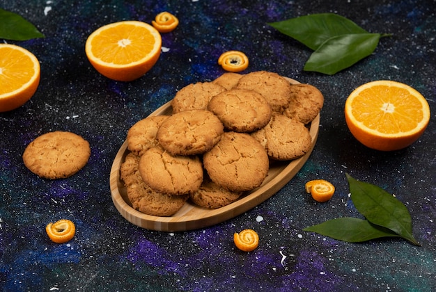 Bezpłatne zdjęcie na pół cięte pomarańcze i pół cięte domowe ciasteczka na desce nad powierzchnią przestrzeni.
