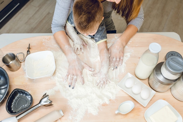 Bezpłatne zdjęcie na rysunku w zbliżeniu przedstawiono stół kuchenny z dwoma układami rąk: mamy i syna oraz sprzęt kuchenny na stole.