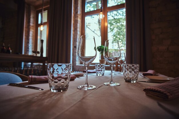 Na stole z białym obrusem stoją kieliszki do wina i wody gotowe do posiłku.