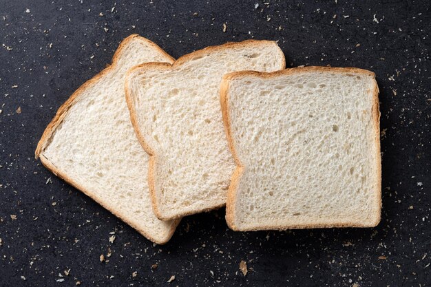 Bezpłatne zdjęcie naciśnięty biały chleb na czarnym tle z łupka