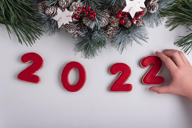 Napis 2022 z piernika, ręka dziecka biorąca ciasteczko. wystrój noworoczny i świąteczny