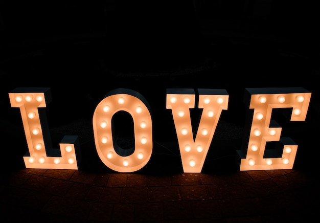Napis LOVE z żółtymi lampami stoi na chodniku