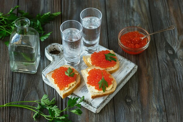 Napój alkoholowy z kawiorem z łososia i tostami z chleba na drewnianej ścianie. Czysty alkoholowy napój rzemieślniczy i tradycyjne przekąski. Negatywna przestrzeń. Świętowanie jedzenia i pyszne. Widok z góry.