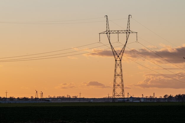 Napowietrzna linia energetyczna na wsi o zachodzie słońca