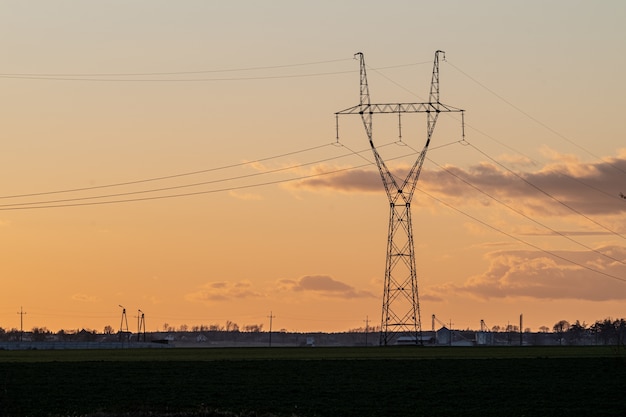 Napowietrzna linia energetyczna na wsi o zachodzie słońca