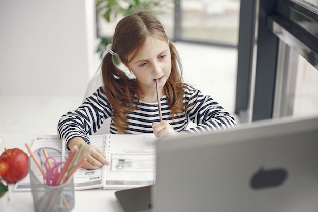 Nastolatek dziewczyna patrząc na laptopa. chiln w okresie kwarantanny podczas pandemii. nauka w domu. dystans społeczny. test szkolny online.