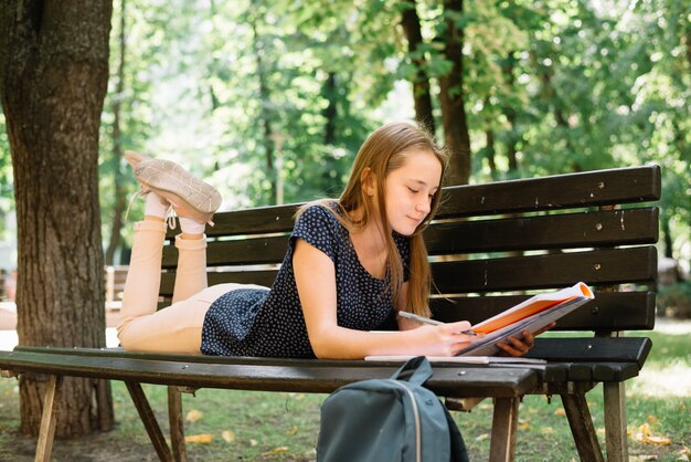 Nastolatek studiuje na ławce w parku