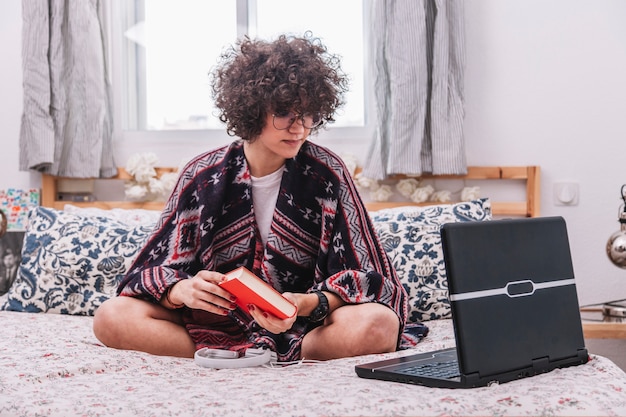 Bezpłatne zdjęcie nastolatek z książką i laptopem na łóżku
