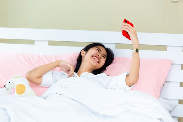 Nastolatka kobieta korzysta ze smartfona na czacie na łóżku