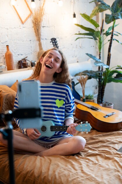 Nastolatka nagrywa muzykę w domowym studiu z gitarą