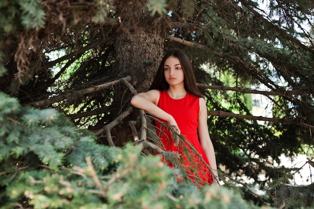 Nastolatka w czerwonej sukience pozowała na zewnątrz w słoneczny dzień