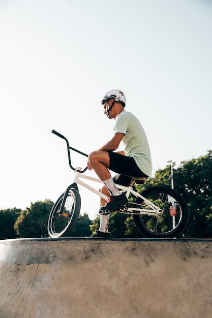 Nastoletnia bmx jeźdza pozycja z jego roweru niskiego kąta widokiem