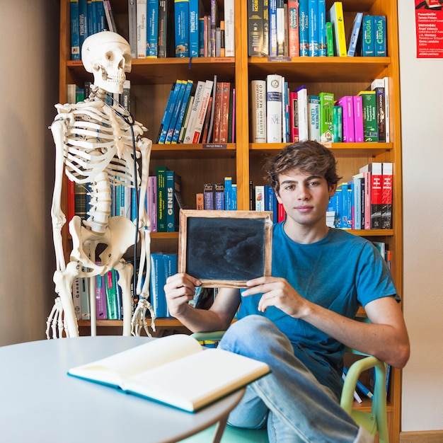 Nastoletnia chłopiec pokazuje blackboard w bibliotece
