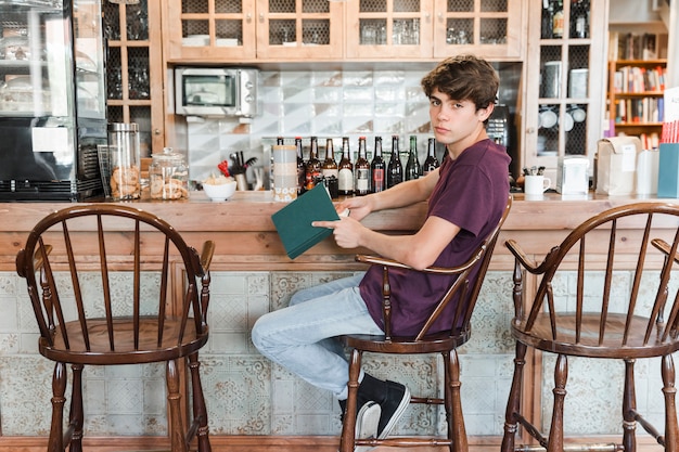 Nastoletnia chłopiec z książkowym pobliskim rocznikiem odpierającym w kawiarni