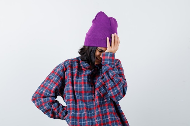 Bezpłatne zdjęcie nastoletnia kobieta w kraciastej koszuli i czapce wygląda na zirytowaną