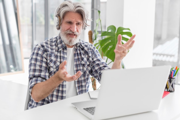 Bezpłatne zdjęcie nauczyciel przy biurku mówi do laptopa