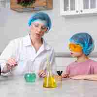 Bezpłatne zdjęcie nauczycielka i dziewczyna z sieci na włosy robi eksperymenty naukowe