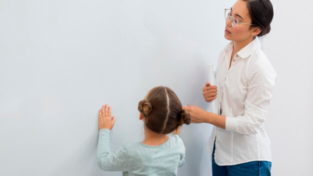 Nauczycielka mówi swojemu uczniowi, co ma pisać na białej tablicy
