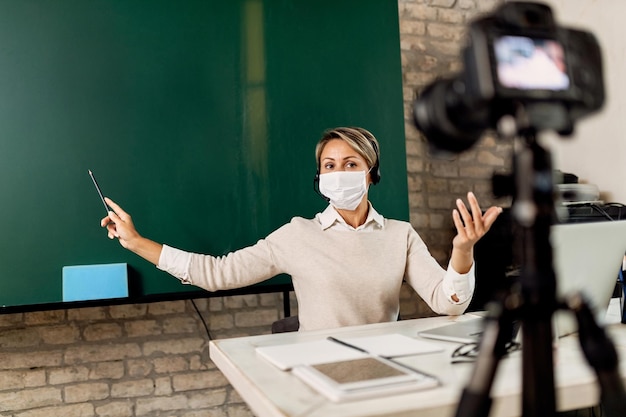 Bezpłatne zdjęcie nauczycielka wskazująca na tablicę podczas prowadzenia zajęć online z powodu pandemii covid19