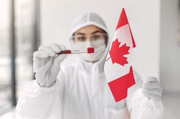 Naukowiec w kombinezonie z próbką koronawirusa i kanadyjską flagą