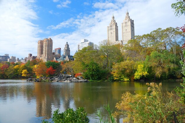 New York City Central Park jesienią z wieżowcami Manhattanu i kolorowymi drzewami nad jeziorem z odbicia.