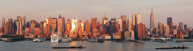 New York City Manhattan skyline panorama o zachodzie słońca z Empire State Building i drapacze chmur z odbicia nad rzeką Hudson.