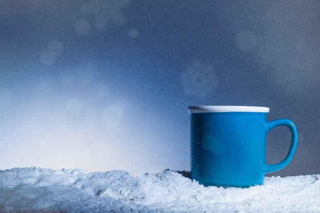 Niebieska filiżanka umieszczona na śniegu