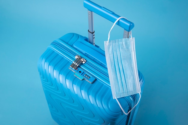 Niebieska walizka podróżna z maską medyczną
