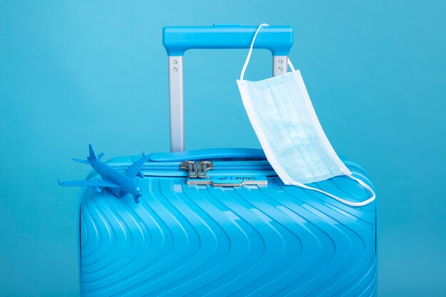 Niebieska walizka podróżna z maską medyczną