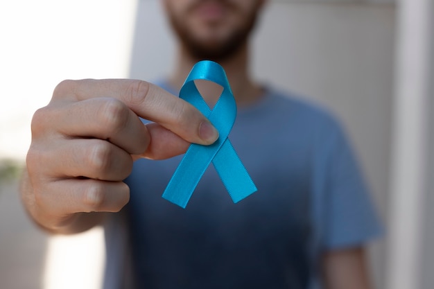 Niebieski listopad. miesiąc profilaktyki raka prostaty. mężczyzna trzyma niebieską wstążkę. zdrowie mężczyzn.