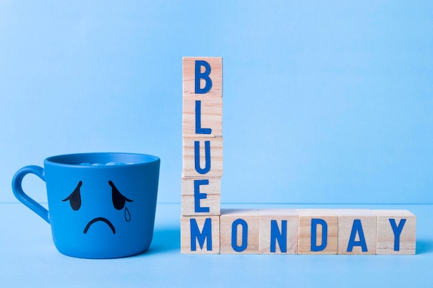 Bezpłatne zdjęcie niebieski poniedziałek z drewnianymi kostkami i łzawym kubkiem