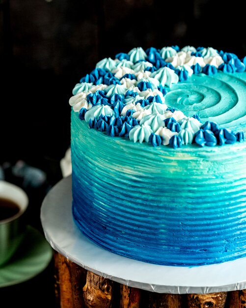 Niebieskie okrągłe ciasto ozdobione niebieskimi kremowymi kwiatami