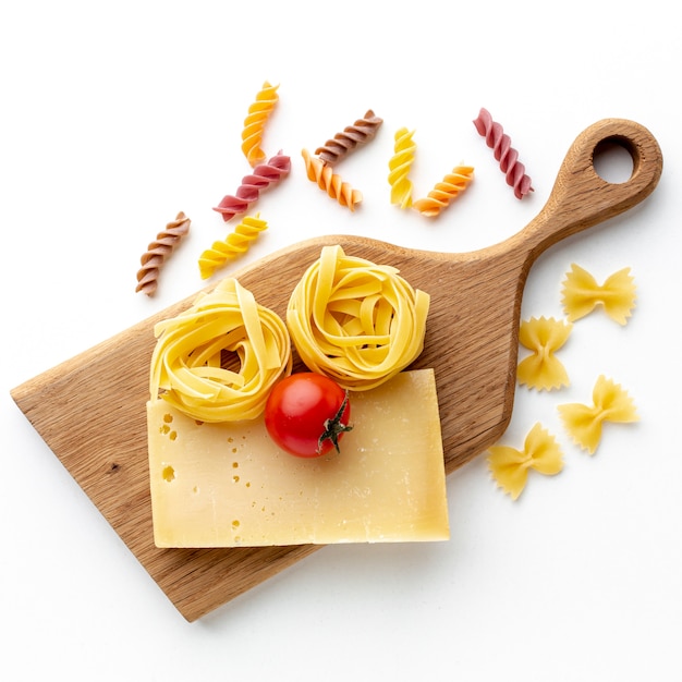 Bezpłatne zdjęcie niegotowane fusilli tagliatelle farfalle z twardym serem i pomidorem