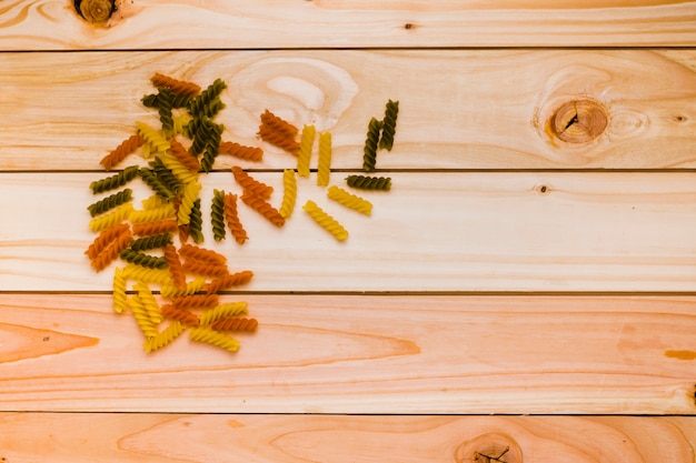 Niegotowane tricolor fusilli makaron na tradycyjne dania kuchni włoskiej na drewnianym biurku