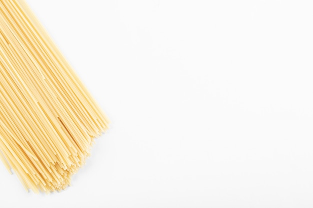 Niegotowany makaron spaghetti na białym tle.