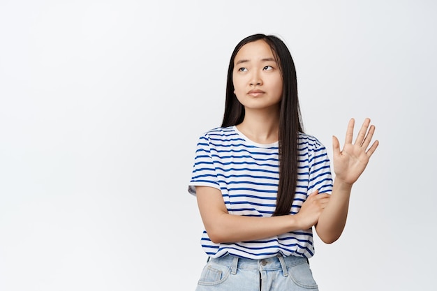 Nierozbawiona arogancka Azjatka pokazująca gest dłonią odwracająca wzrok z niechęcią odmawiającą czegoś pokazuje znak odrzucenia na białym tle