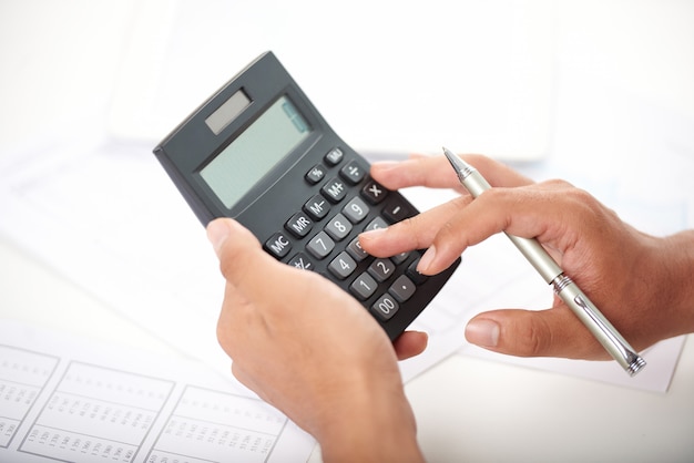 Bezpłatne zdjęcie nierozpoznany pracownik biurowy za pomocą kalkulatora