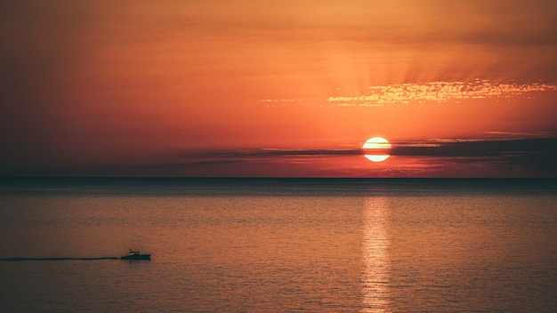Bezpłatne zdjęcie niesamowite ujęcie pięknego krajobrazu morskiego na pomarańczowym zachodzie słońca