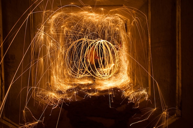 Niesamowity ogień z wełny stalowej krąży w nocy ze świecącymi iskrami