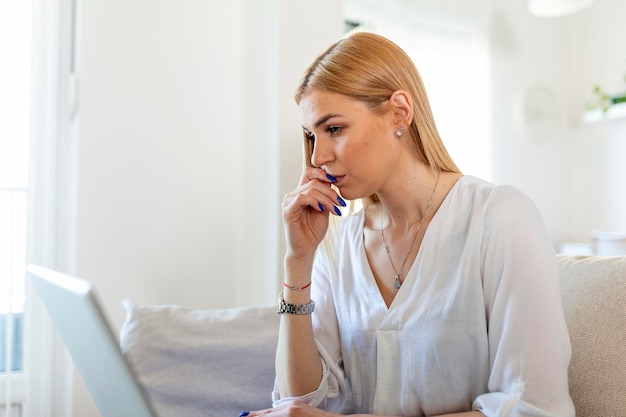 Bezpłatne zdjęcie niespokojna, przygnębiona kobieta siedzi z laptopem, wygląda na zdenerwowaną, zmartwioną, boi się stresującej pracy na czas