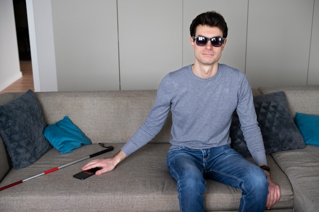 Niewidomy mężczyzna wyjmujący smartfon z kanapy