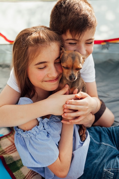 Niewinnie uśmiechnięte rodzeństwo kochające swoje zwierzątko w namiocie