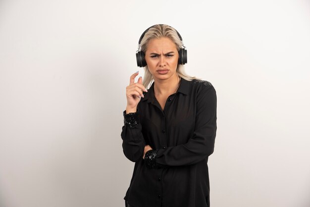 Niezadowolona kobieta ze słuchawkami stojąc na białym tle. Wysokiej jakości zdjęcie