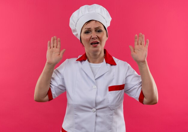 Niezadowolona kucharka w średnim wieku w mundurze szefa kuchni, podnosząca ręce