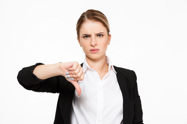 Niezadowolona poważna blondynki biznesowa kobieta pokazuje kciuka puszek