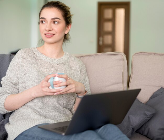 Bezpłatne zdjęcie niezależna kobieta na leżance pracuje na laptopie