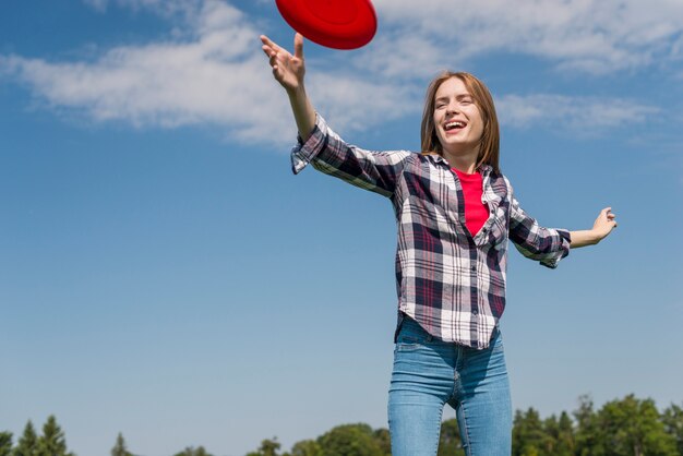 Niski kąt blondynki dziewczyna bawi się z czerwonym frisbee