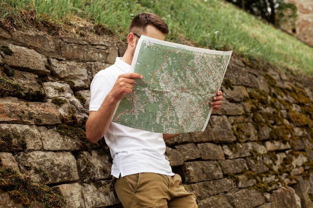 Bezpłatne zdjęcie niski kąt młody człowiek czytanie mapy