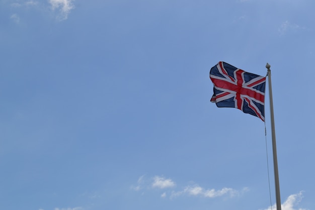 Niski kąt strzału flagi Wielkiej Brytanii na słupie pod pochmurnym niebem